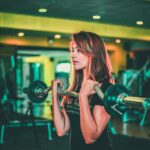 woman lifting black and gray barbell