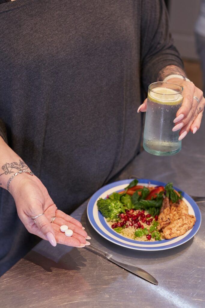 a person holding a jar of liquid over a plate of food